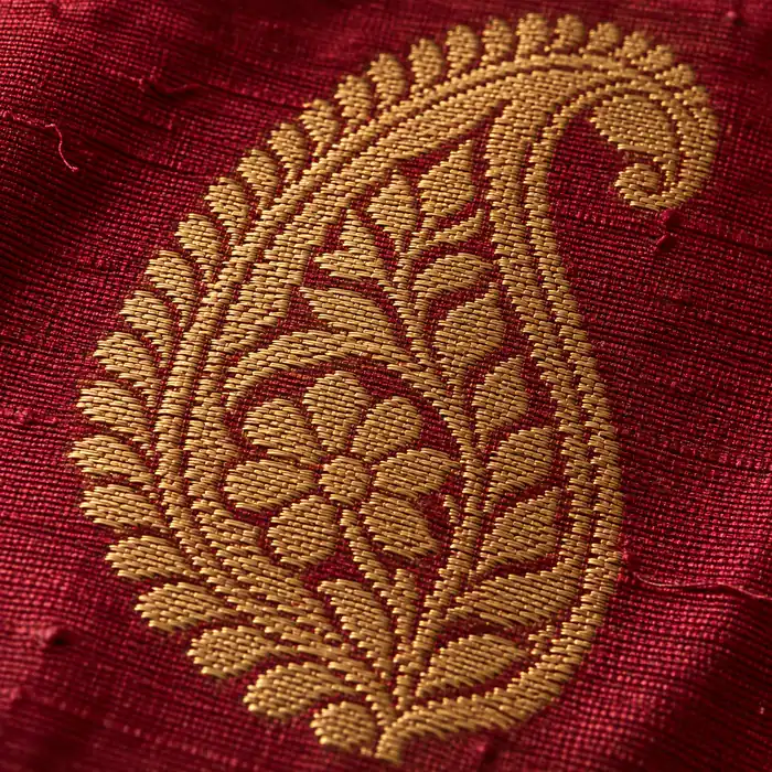 Close-up of a paisley motif woven flat in gold zari into lac-red silk